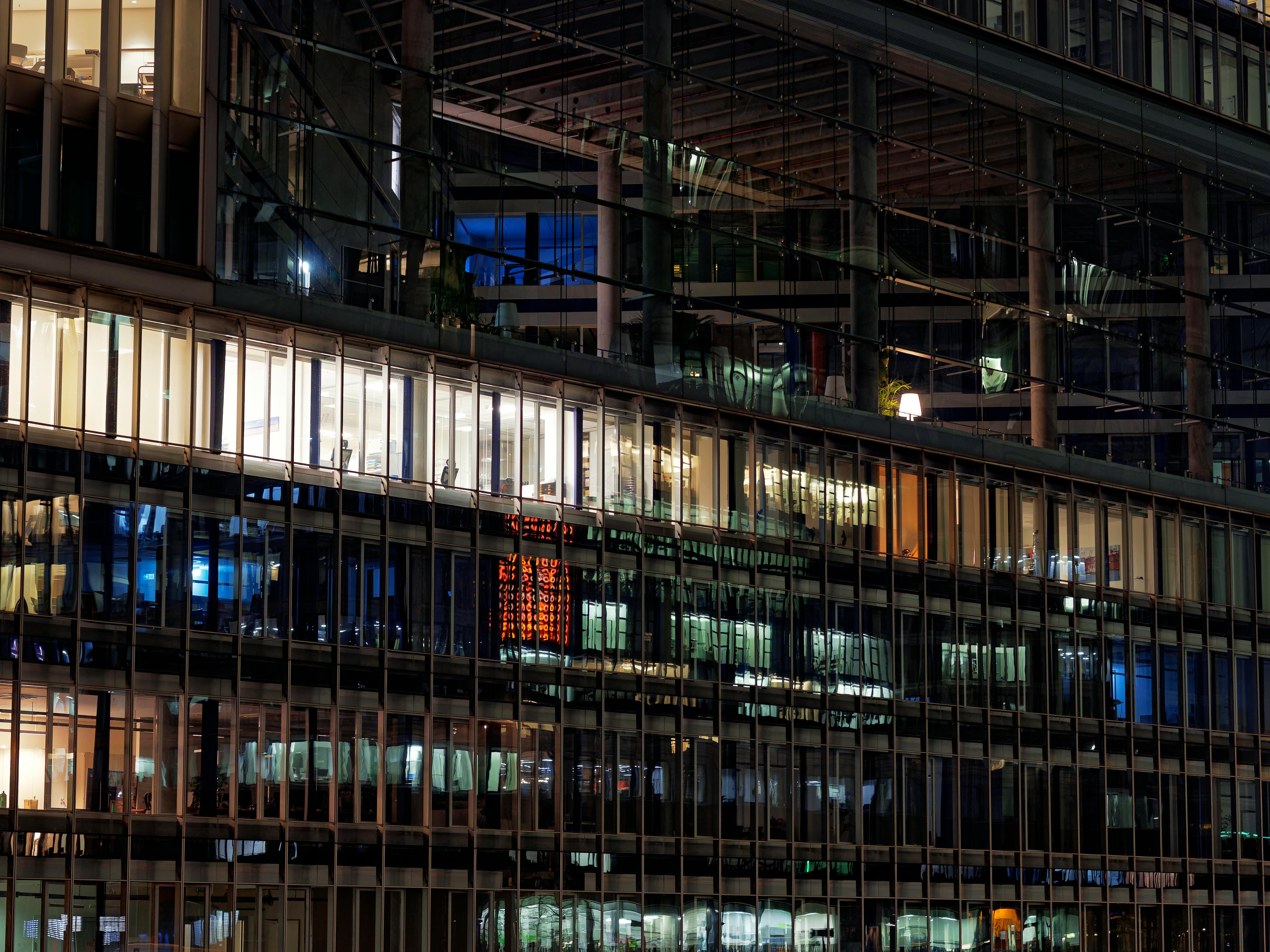 Fachada urbana de vidrio con oficinas iluminadas durante la noche